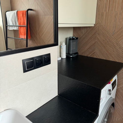 alt="Nowoczesna łazienka z czarnym blatem i białymi ścianami"